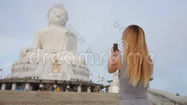慢动作记者女孩用智能手机制作泰国佛像的照片。